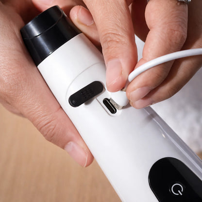 Person plugging a white USB cable into a black and white electronic device.